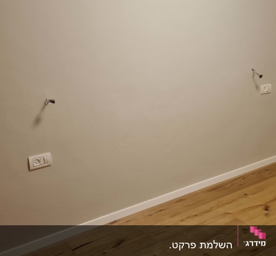 רצפת פרקט עם קיר לבן ושקעי חשמל